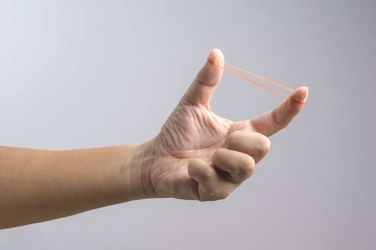 Hand holding elastic rubber band on white background