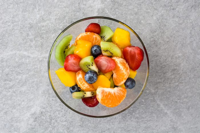 Fruit salad in crystal bowl on gray stone. Top view