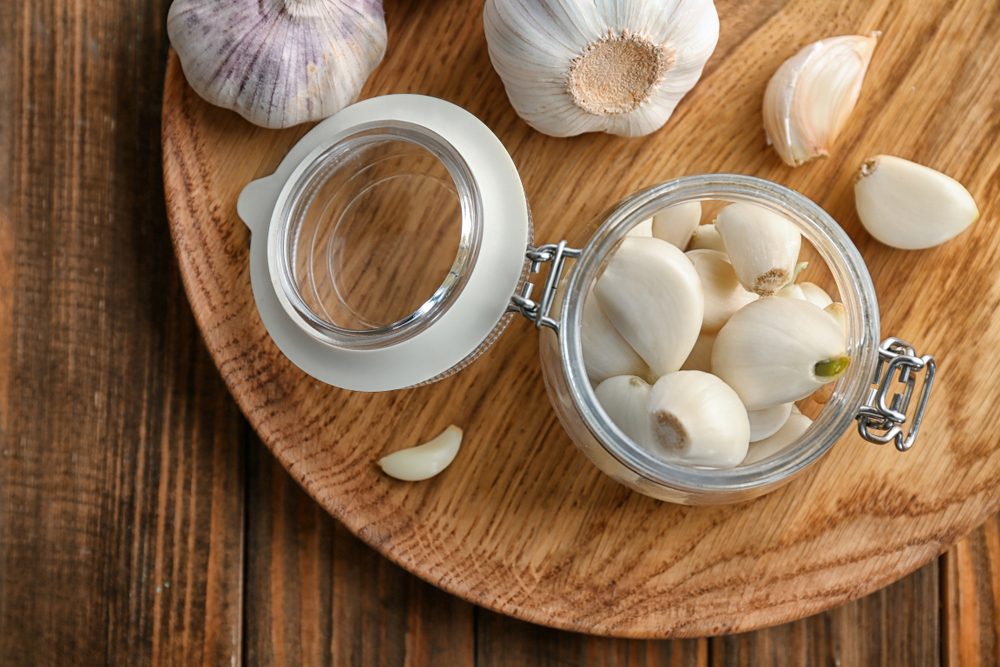 Jar with garlic cloves and heads on plate