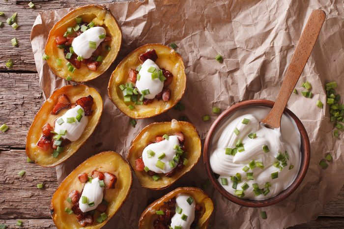 Rustic potato skins with cheese, bacon and sour cream close-up on the table. Horizontal view from above