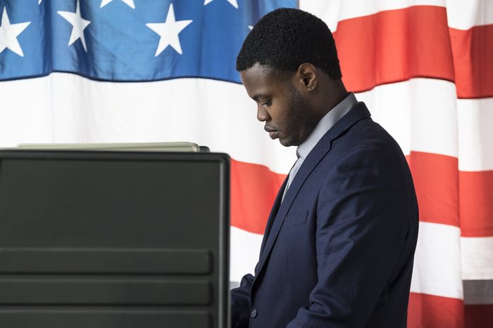 A young man in a voting booth, side view