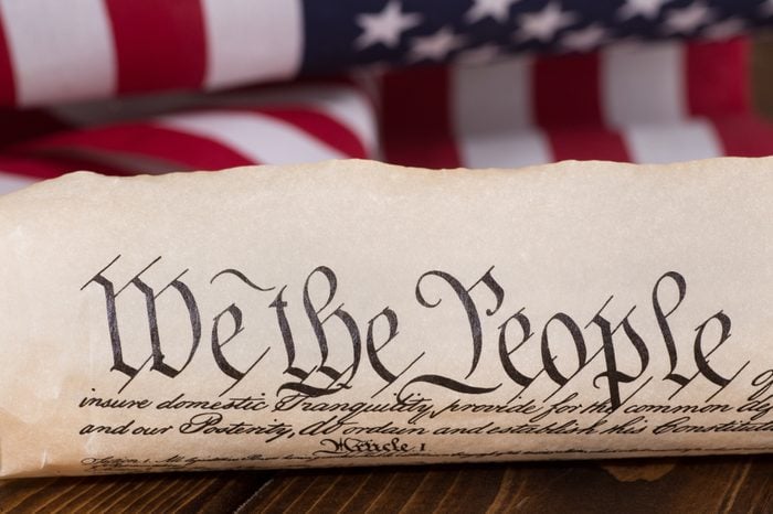 Document text "We the People" of the preamble to the United States constitution with american flag in background