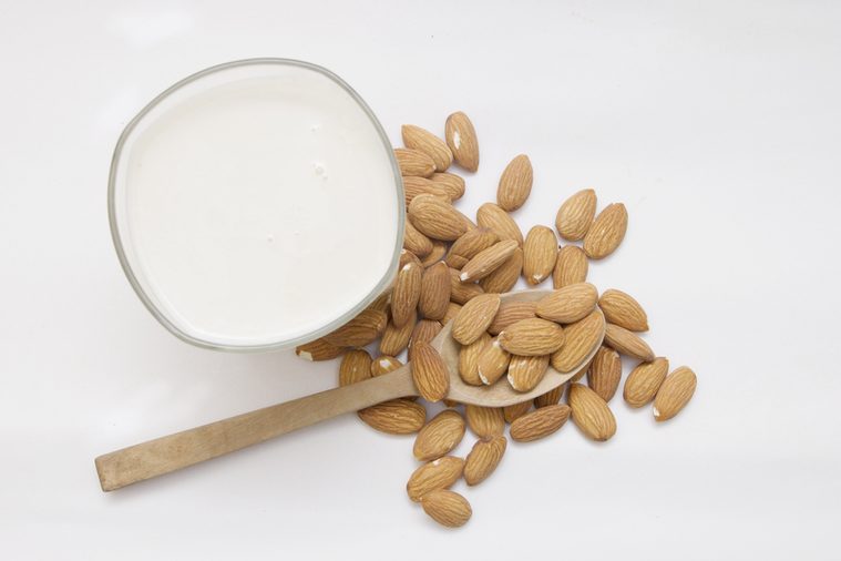 Almond milk in glass with nuts isolated on white background
