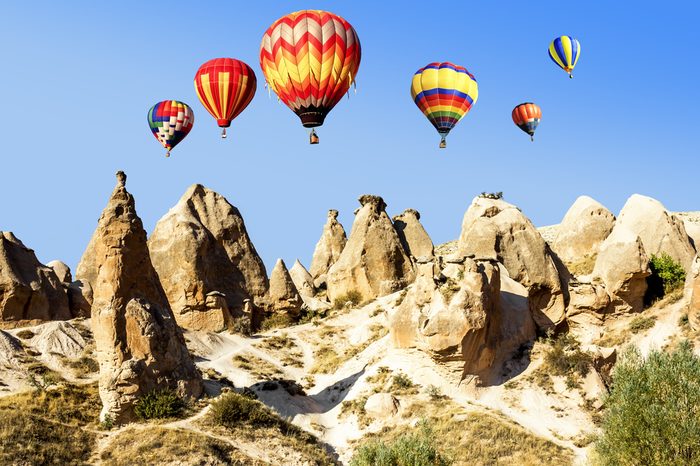 Balloons over the volcanic mountain landscape of Cappadocia in a bright sunny day