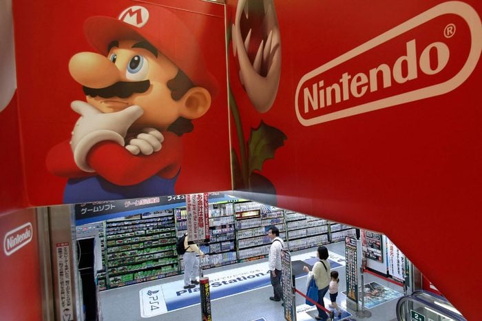Shoppers walk under the logo of Nintendo and Super Mario characters at an electronics store in Tokyo . Nintendo Co. sank to a loss for the fiscal year ended March as sales of its Wii U game machine continued to lag, but the Japanese manufacturer of Pokemon and Super Mario games promised Wednesday to return to profit this year