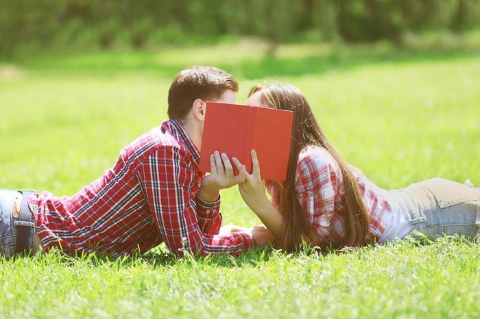 Couple students in love kissing on the grass