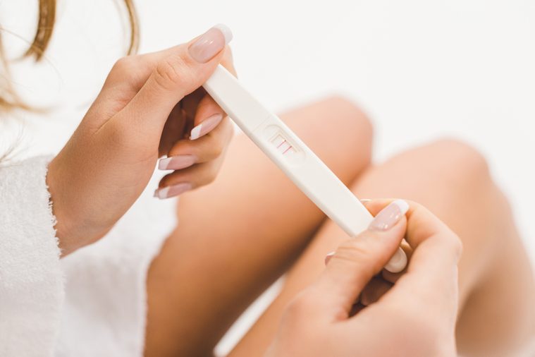 partial view of woman holding pregnancy test in hands