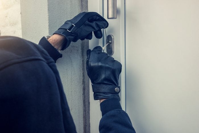 burglar holding Lock-picker to open a housedoor