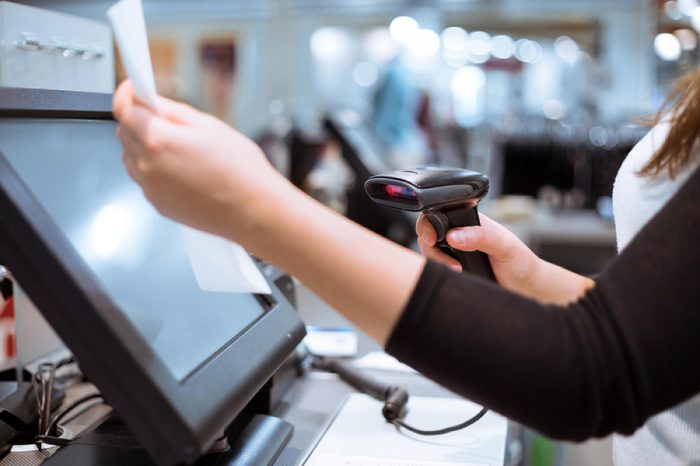 Young woman hands scaning / entering discount / sale on a receipt, touchscreen cash register, market / shop