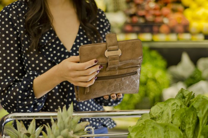 Young woman opening wallet at the supermarket