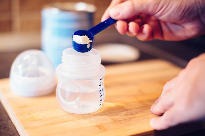 Father making baby formula in milk bottle for a newborn baby feed