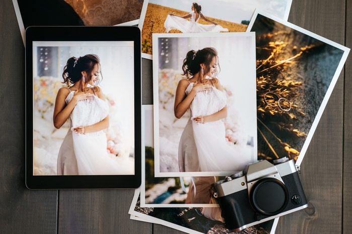 Printed wedding photos with the bride, a vintage black camera and a black tablet with a picture of bride