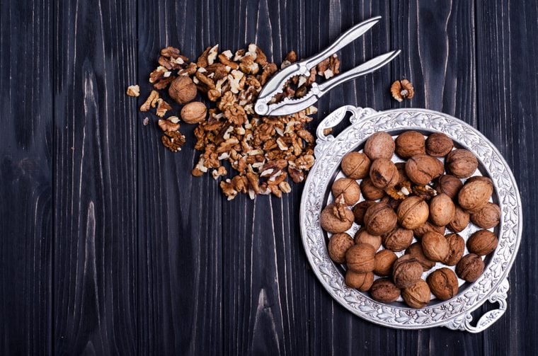 Walnut kernels and whole walnuts on a black wooden background. Top view