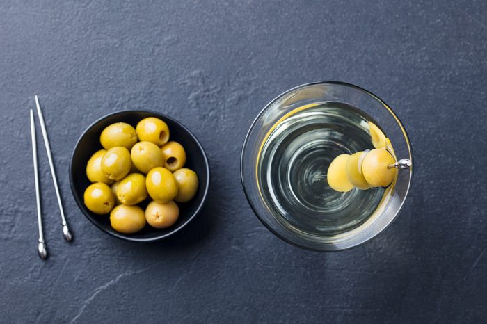 Martini cocktail with green olives. Slate background. Top view.