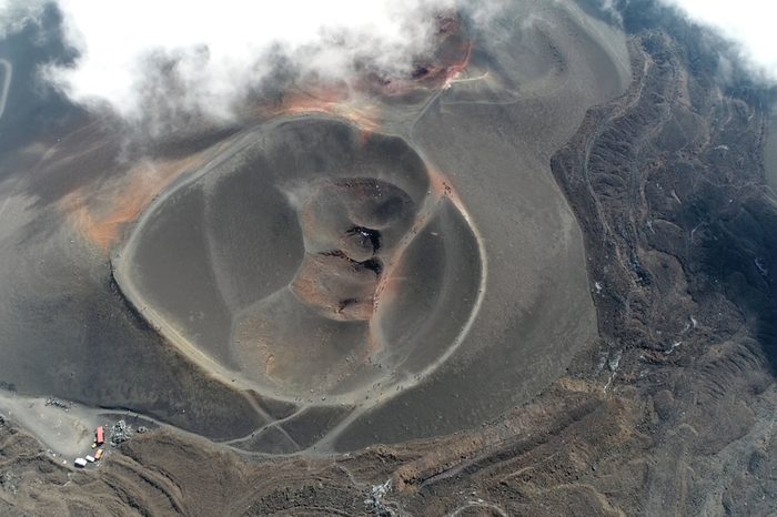 Aerial picture Mount Etna volcanic crater one of the flank craters is roughly circular depression in ground caused by volcanic activity and is typically bowl-shaped feature also showing people walking