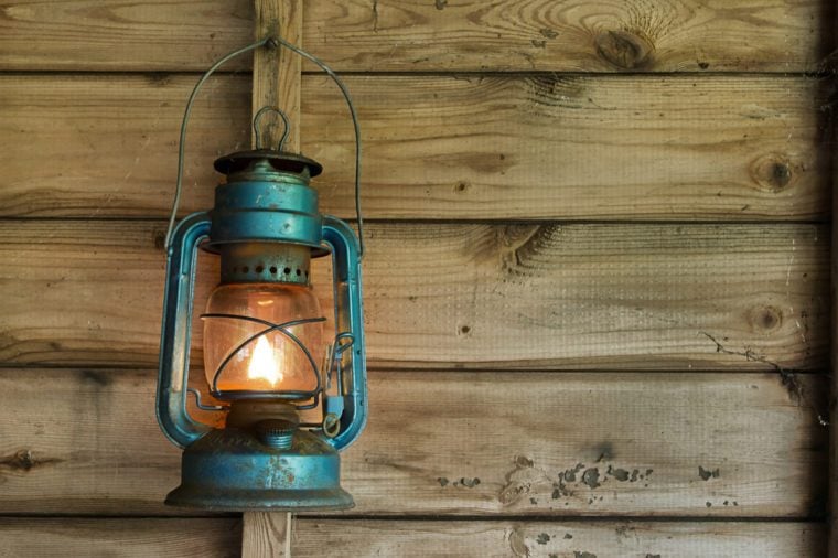 Rusty lit blue lantern hanging in an old shed