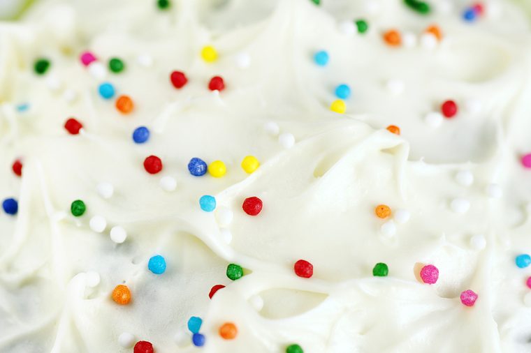 Great appetizing background of cream cheese cake frosting or icing with colorful sugar candy.