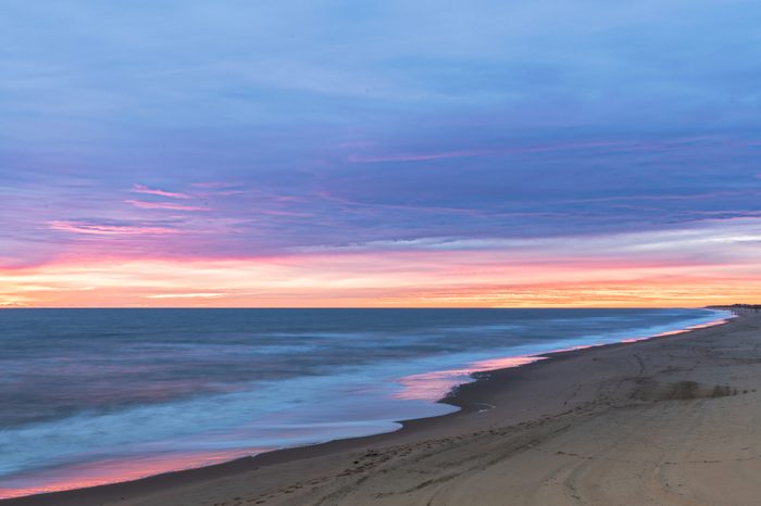 Sunrise along the Atlantic Ocean in Virginia Beach at Little Island Park in Sandbridge. The sun creates pink and purple pastel reflections on the surf
