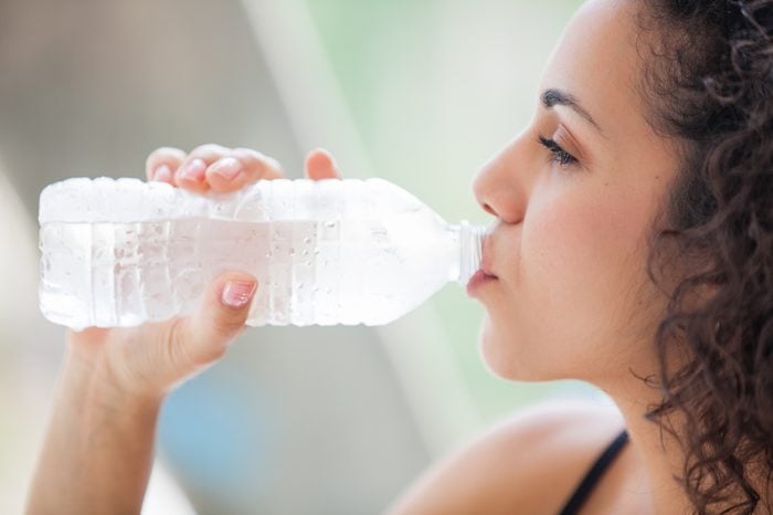 Pretty young woman drinking a bottle of ice cold water