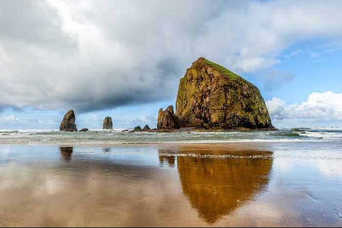 Oregon coast scenic Haystack Rock on a dramatic day with clouds and reflections. Famous destination for bird watchers.