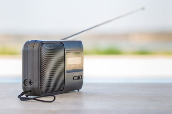 A small transistor radio with a string cord handle outside.