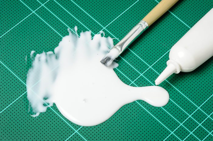 closeup white latex adhesive spilling on cutting mat