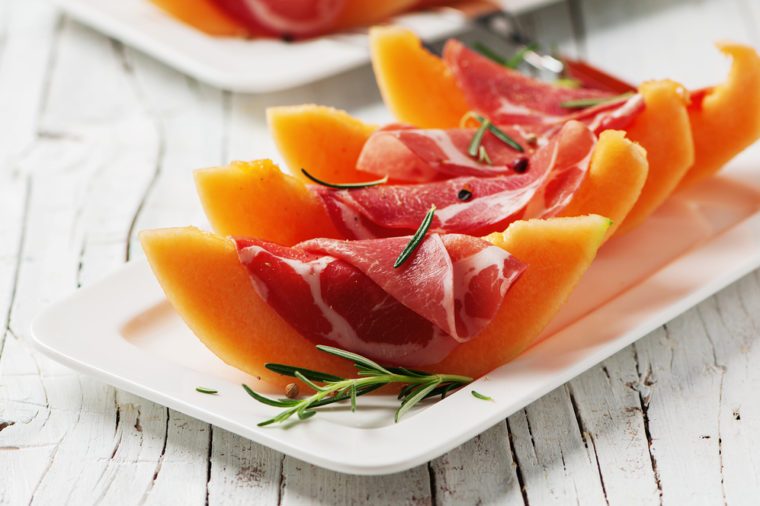 Concept of italian food with melon and prosciutto, selective focus
