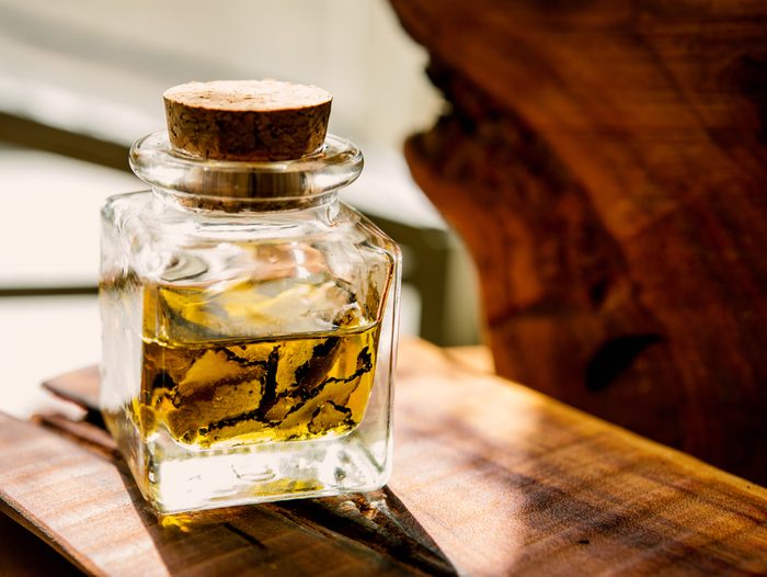 mushrooms black truffle in the bottle with oil It is standing on a wooden board in front of sunlight