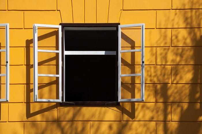 open window with white frames, yellow bricks and some shadows