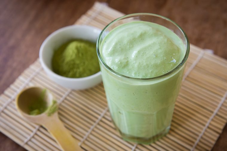 Green tea smoothie blended beverage with matcha powder and spoon