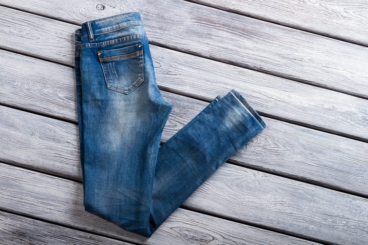Folded blue jeans. Denim pants on wooden background. Woman's new casual jeans. Last item at special price.