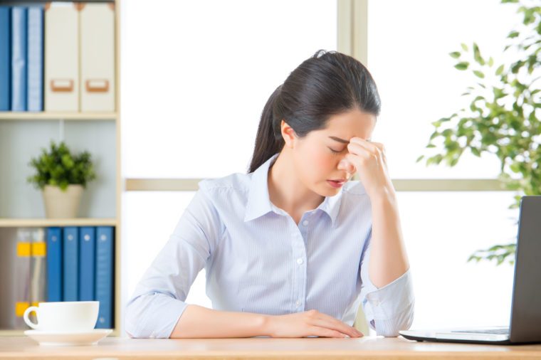 Young asian business woman with headache in office