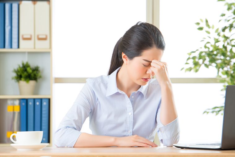 Young asian business woman with headache in office