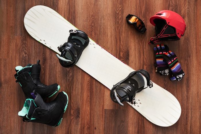 set of snowboard equipment boots, helmet, gloves and mask on a wooden floor