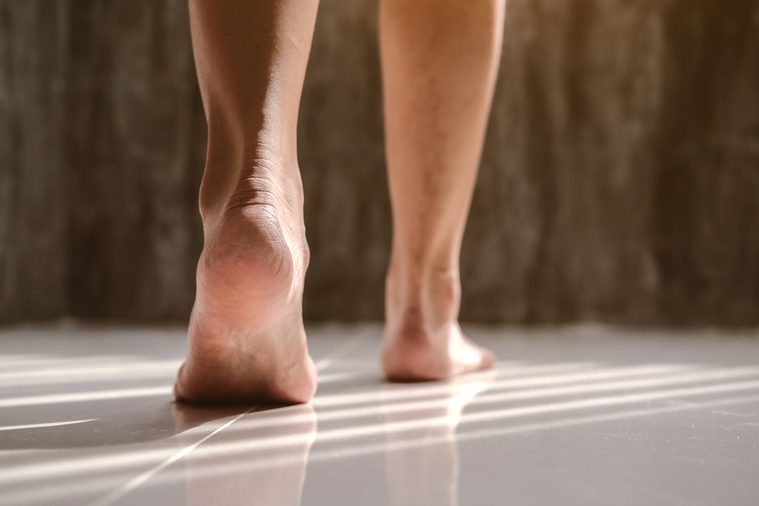 Female feet walking on floor brick room with sunlight