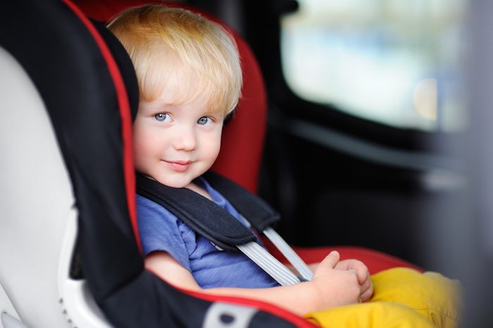 Portrait of pretty toddler boy sitting in car seat. Child transportation safety