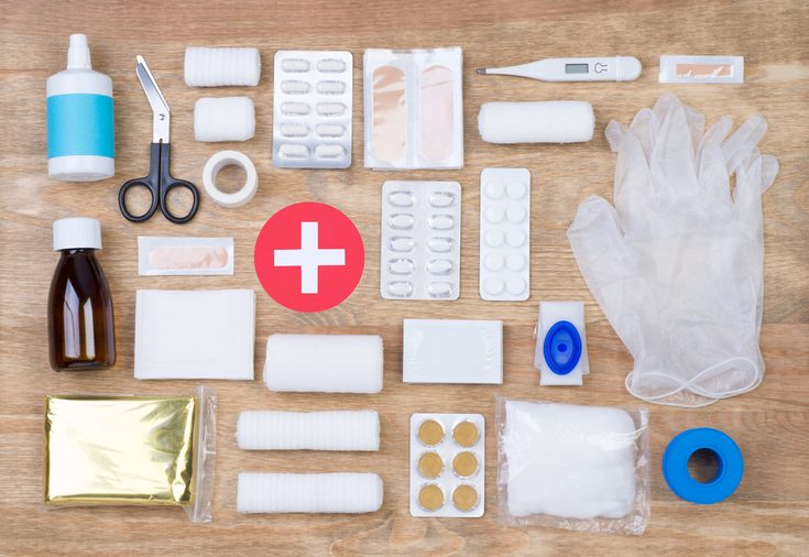 First aid kit on wooden background, top view