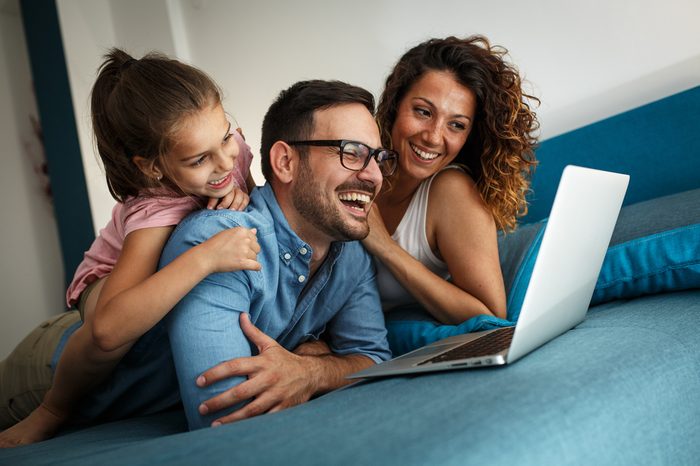Happy family lies on bed and watching something on laptop.Laughing and fun.