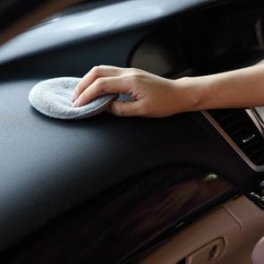 woman hand cleaning leather black console in car with soft fabric sponge waxing polished