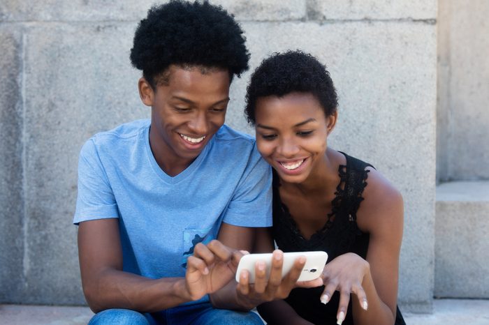 Joyful laughing african american couple looking at phone