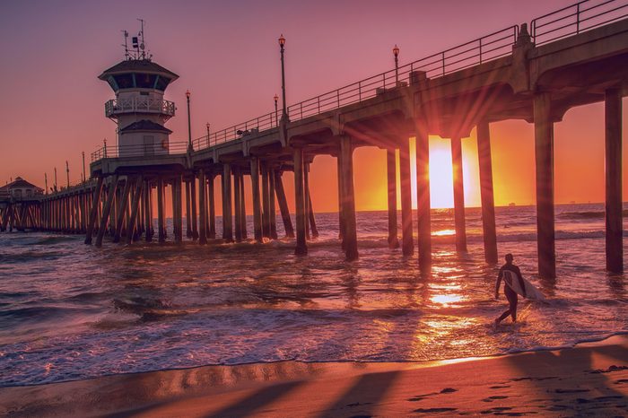 Silhouette of a surfer at sunset in front of the Huntington Beach Pier in California