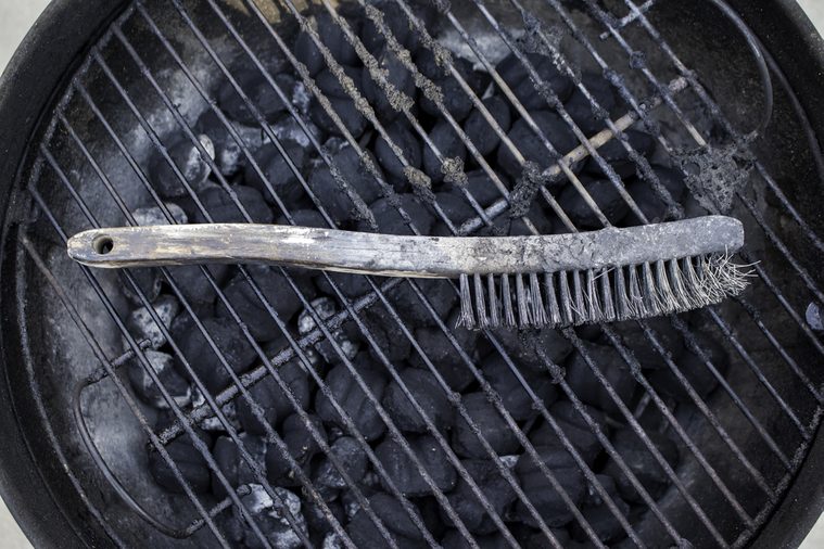 Grill brush resting on a dirty grill.
