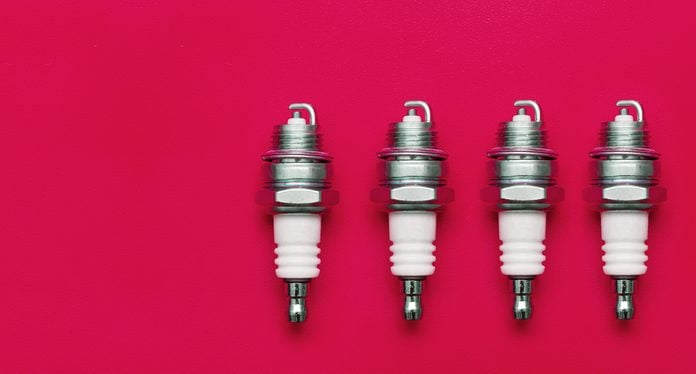 Spark plug. A set of spark plugs. Four spark plugs. Four spark plugs on a pink background.
