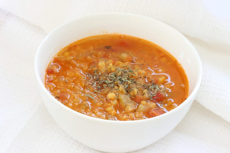 View of red lentil soup in white bowl,