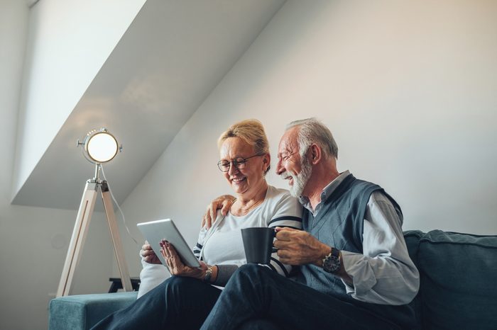 Elderly couple holding a digital tablet laughing