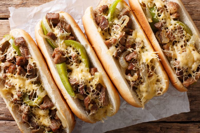 Philadelphia cheesesteak sandwich close-up on paper on the table. Horizontal top view from above