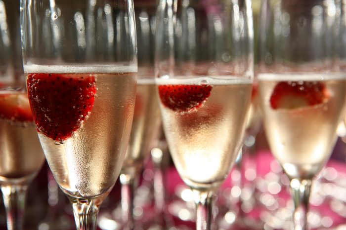 Champagne glass with strawberries inside close up with many other glasses