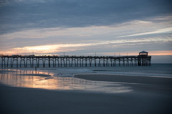 sunset at the north carolina beach with atlantic beach pier and sunrise with sand and water in the foreground