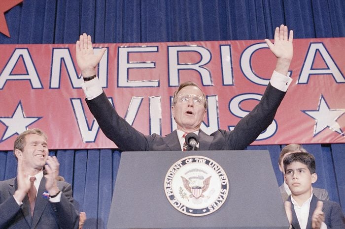 President-elect George H. W. Bush holds his hands up to acknowledge the crowds applause, and ask them to allow him to continue his speech, during his victory rally with grandson, George P. Bush, right, and son George W. Bush, left, Houston, Texas