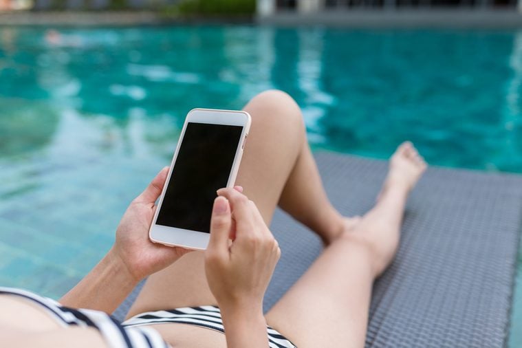 Woman enjoy sun bath and using mobile phone in swimming pool